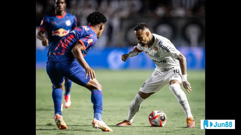 Cầu thủ Bragantino với áo đỏ đang chạy nhanh trước sự truy đuổi của cầu thủ Santos với áo…